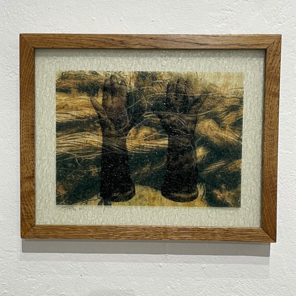 Pennie Baxter, "Hands Up", 2020, Original photographs printed on two layers of textured glass, 
$375 - 

I watched the tv, transfixed, as Black Lives Matter protesters marched with hands in the air, chanting “Hands Up”. That imagery of all those hands in the air inspired this work. The glass layer in the front is of old rotting rope, a binding element meant to portray the struggle people of color have always faced at our hands. The glass layer in the back is of dolls hands, which survived the Camp Fire. They represent the innocence and purity we’ve battered for centuries, evidenced by the distress to the hands. The hands are still whole, despite the pervasive abuse they’ve weathered.

